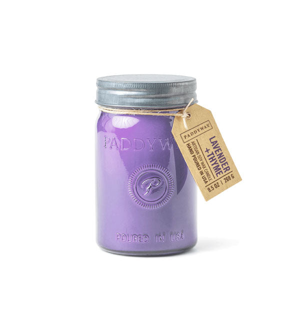 Purple wax candle in glass jar with metal lid and hanging tag that says, "Lavender + Thyme"