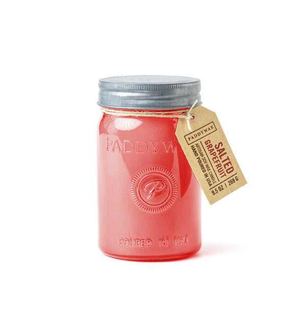Pink wax candle in glass jar with metal lid and hanging tag that says, "Salted Grapefruit"
