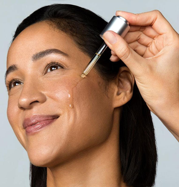 Model applies Dermalogica Active Clearing Retinol Clearing Oil to cheek