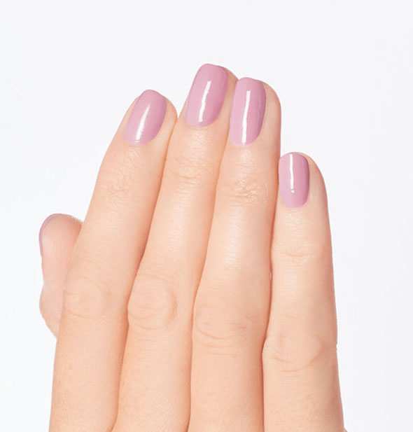 Model's hand wears a muted pink shade of nail polish