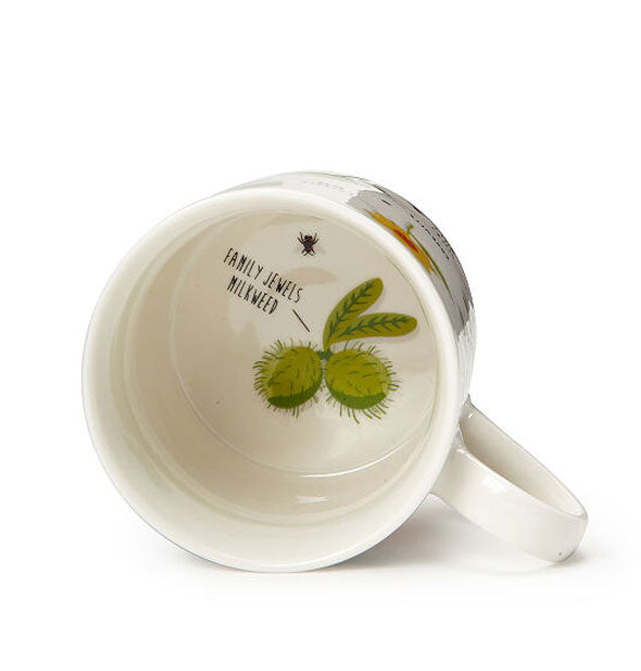 White mug turned on its side features a plant illustration in the bottom with label, "Family Jewels Milkweed"