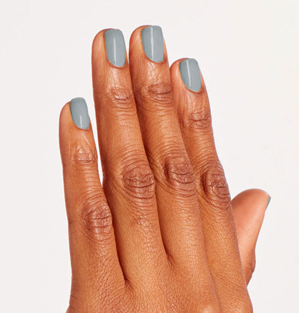 Model's hand wears a steel blue-gray shade of nail polish