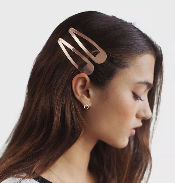 Model wears two large rose gold snap clips at side of head