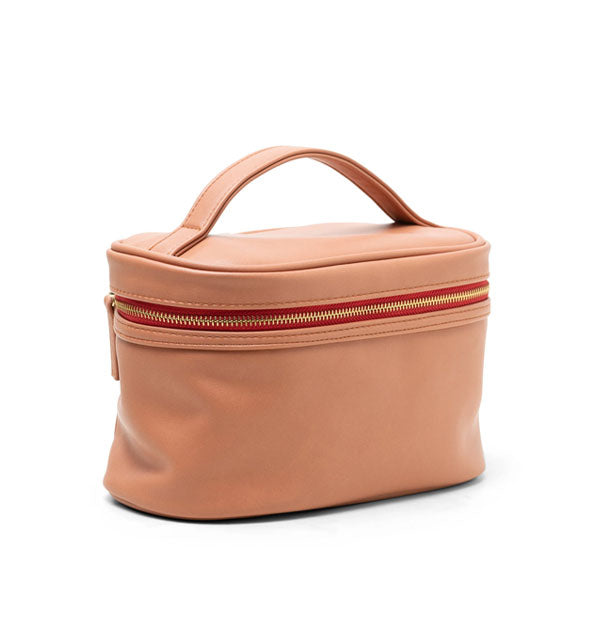 Salmon-colored vegan leather travel case with matching top handle and zipper pull tab, red zipper tape, and gold zipper hardware