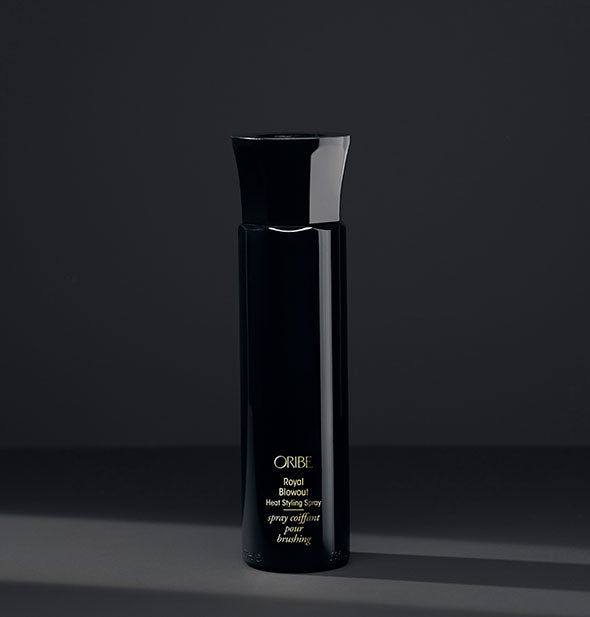 Black bottle of Oribe Royal Blowout Heat Styling Spray on dark gray background