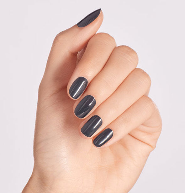 Model's hand wears a dark gray shade of nail polish