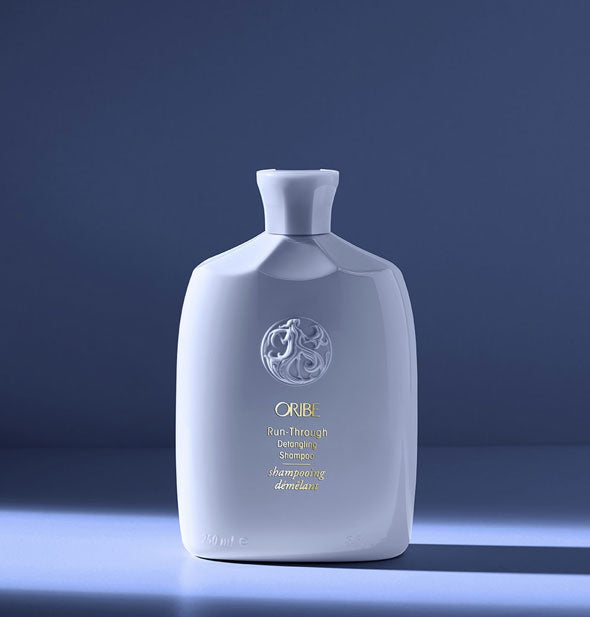 Bottle of Oribe Run-Through Detangling Shampoo on blue background