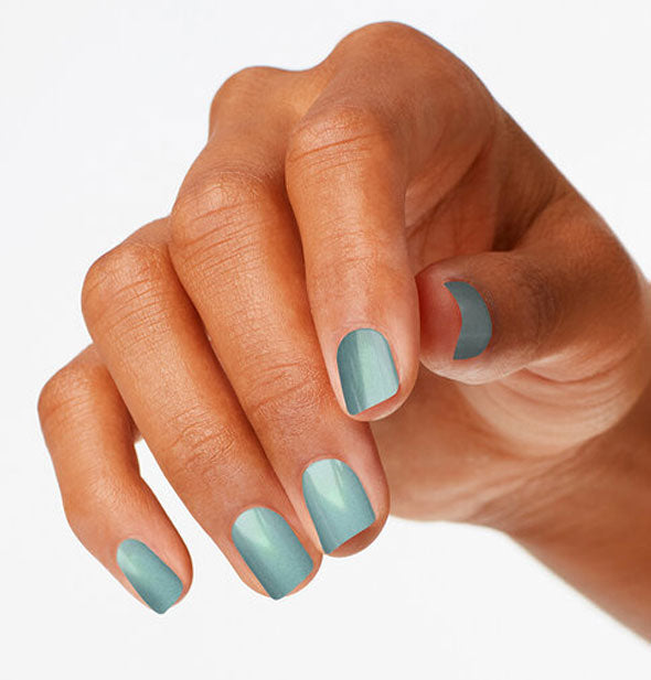 Model's hand wears a shimmery blue-green shade of nail polish