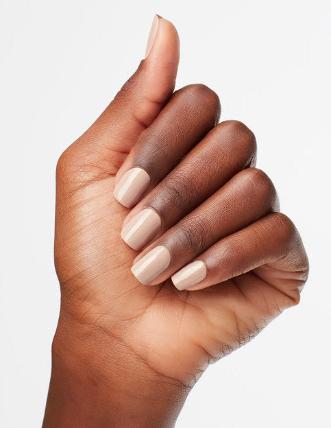 Model's hand wears a light pinkish beige shade of nail polish