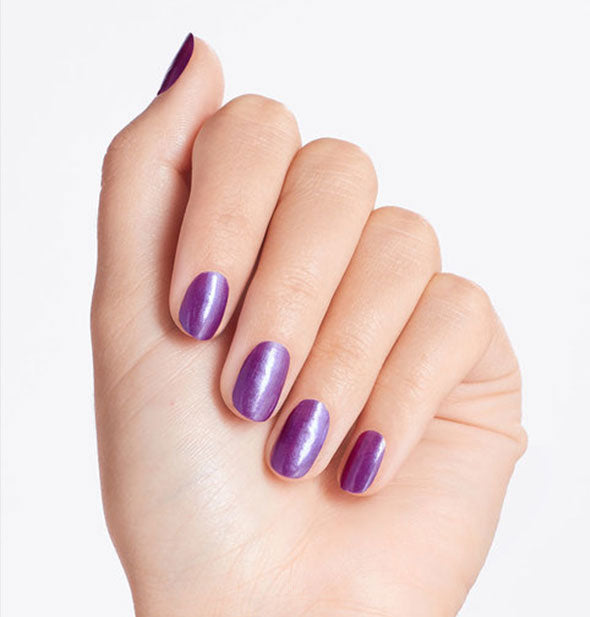 Model's hand wears a shimmery shade of purple nail polish