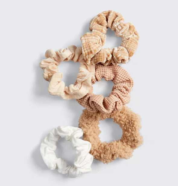 Set of five tan and white hair scrunchies with different textured fabrics