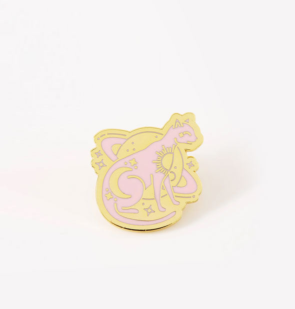 Pink and gold enamel pin is designed with a sitting cat in front of Saturn along with stars and other celestial symbols