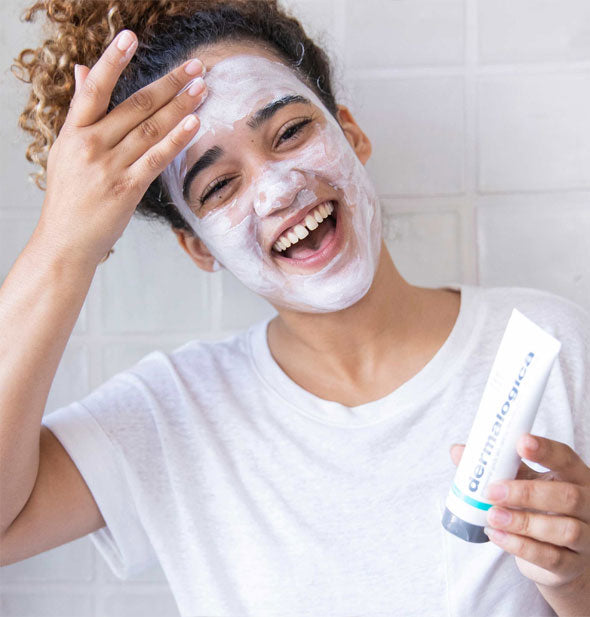 Smiling model applies Dermalogica Sebum Clearing Masque to face