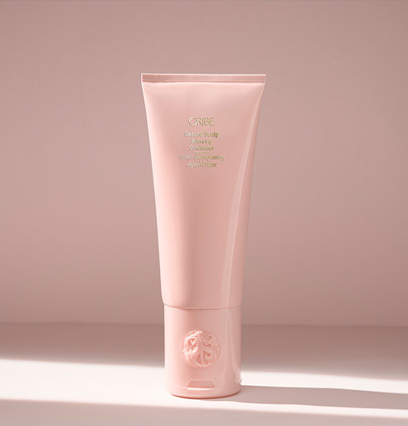 Light pink bottle of Oribe Serene Scalp Balancing Conditioner on blush background