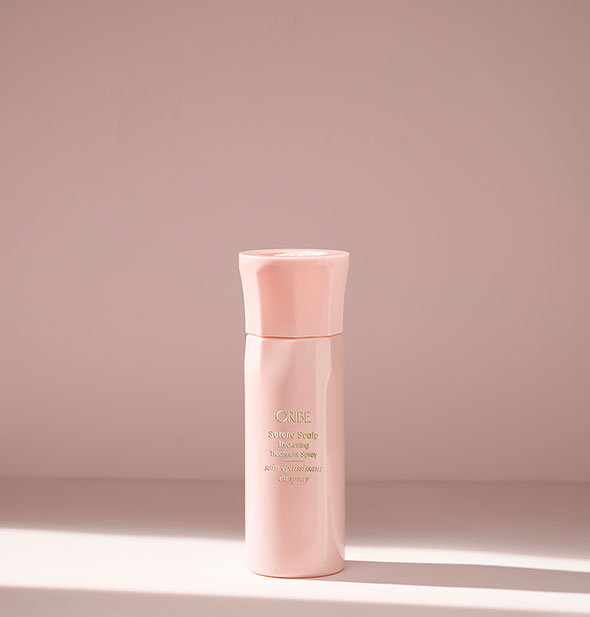 Light pink bottle of Oribe Serene Scalp Thickening Treatment Spray on blush background