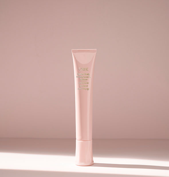 Light pink slender tube of Oribe Serene Scalp Soothing Leave-On Treatment on blush background