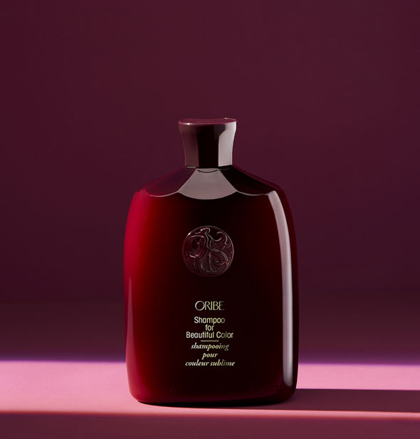 Dark red bottle of Oribe Shampoo for Beautiful Color on burgundy background
