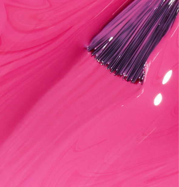 Bright medium pink nail polish with brush tip dipped into it