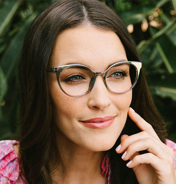 Model wears a pair of rounded cat eye glasses with smoky gray iridescent frame