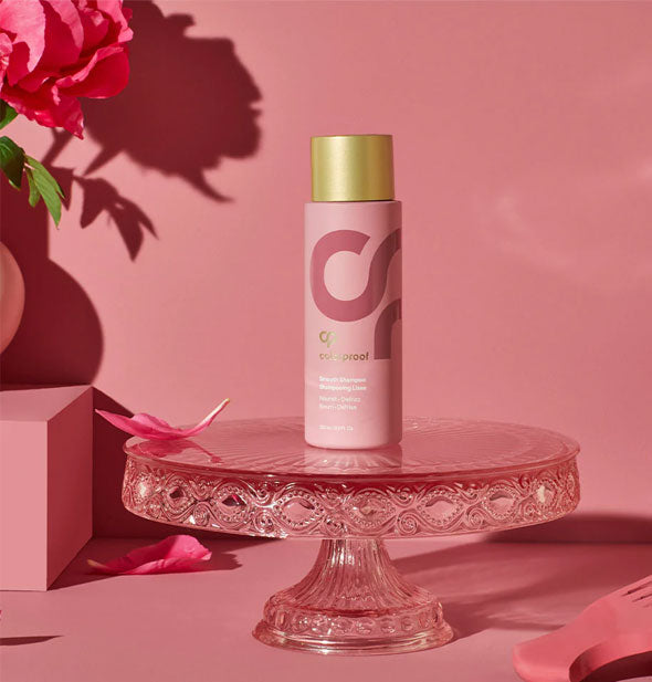 Bottle of ColorProof Smooth Shampoo is staged on a pink crystal pedestal on a pink background with pink flowers and petals