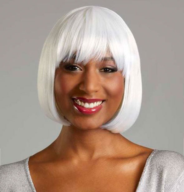 Model wearing a short, pure white wig with bangs.