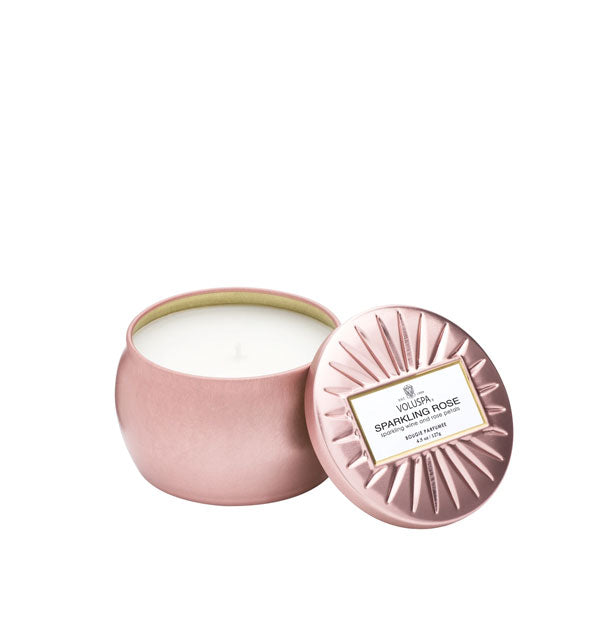 Metallic pink Sparkling Rosé Voluspa candle tin with lid featuring radial embossing set to the side