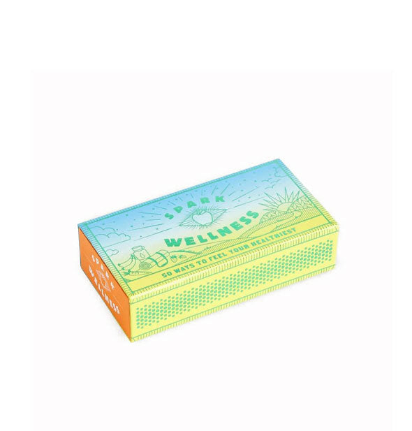 Decorative orange, lime green, and blue Spark Wellness matchbox with illustrated design of a picnic scene in a pastoral setting
