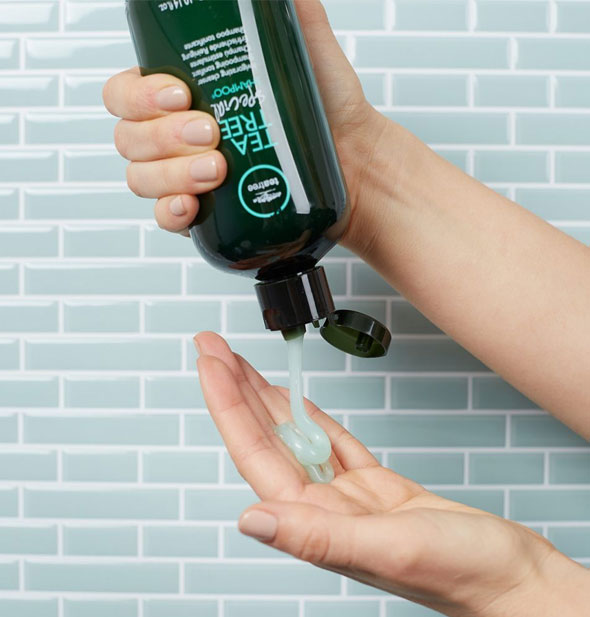 Model dispenses Paul Mitchell Tea Tree Special Shampoo from bottle into hand