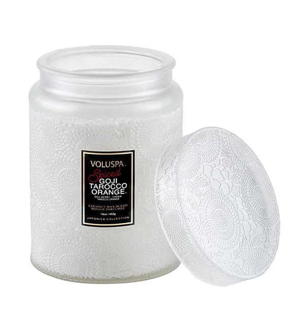 Frosted white embossed glass Spiced Goji Tarocco Orange Voluspa jar candle with matching lid removed and set to the side