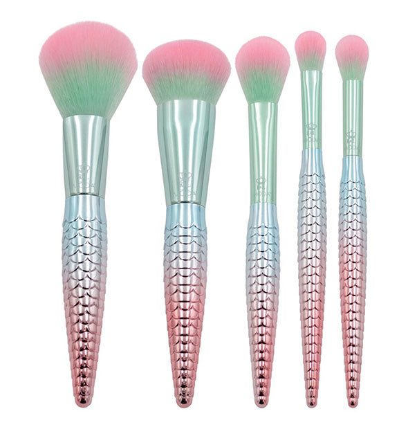 Five makeup brushes with metallic green-to-pink ombré handles that resemble scaled mermaids' tails, and green-to-pink ombré bristles