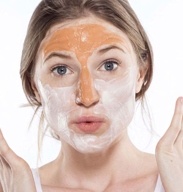 Model with surprised expression has orange face mask applied to forehead and nose and whitish face mask applied to cheeks and chin