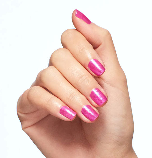 Model's hand wears a dark shade of of shimmery pink nail polish