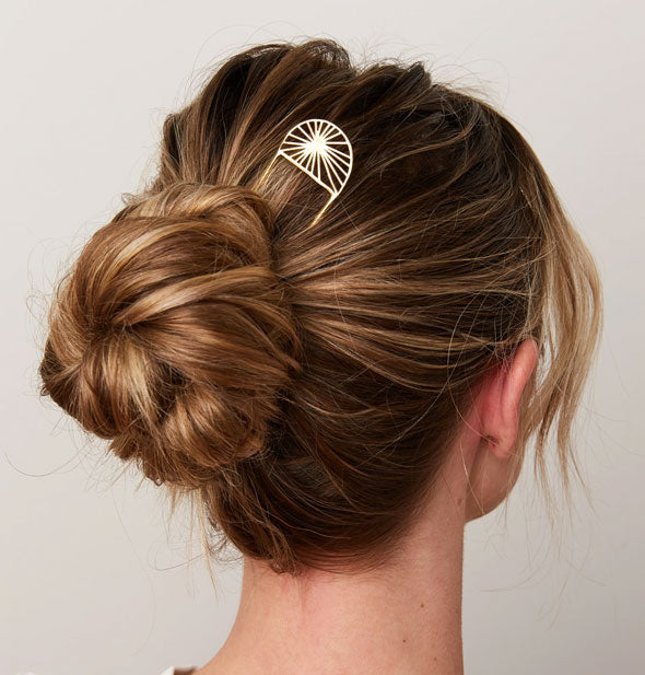 Model wears a brass sunburst hair pick in a twisted updo