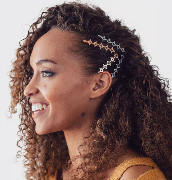 Smiling model wears four starburst hair pins in a swept-back style