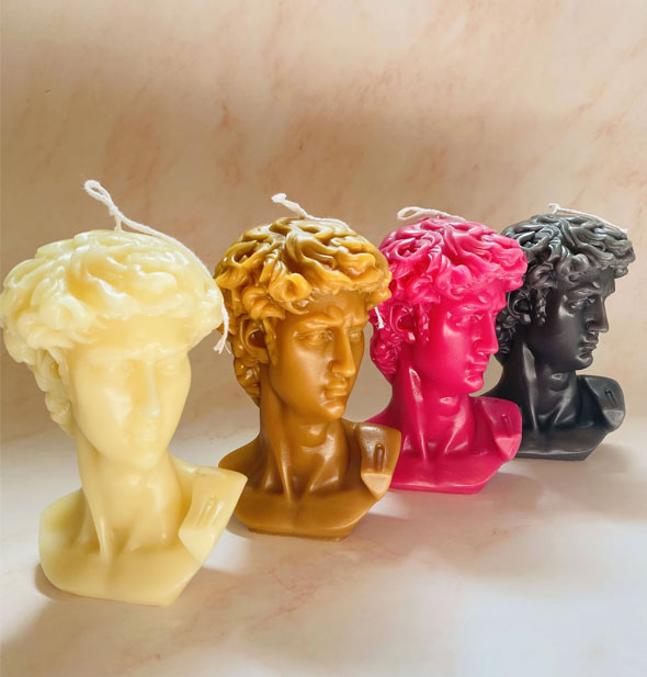 Lineup of four Statue of David bust candles in white, caramel, raspberry, and charcoal colors
