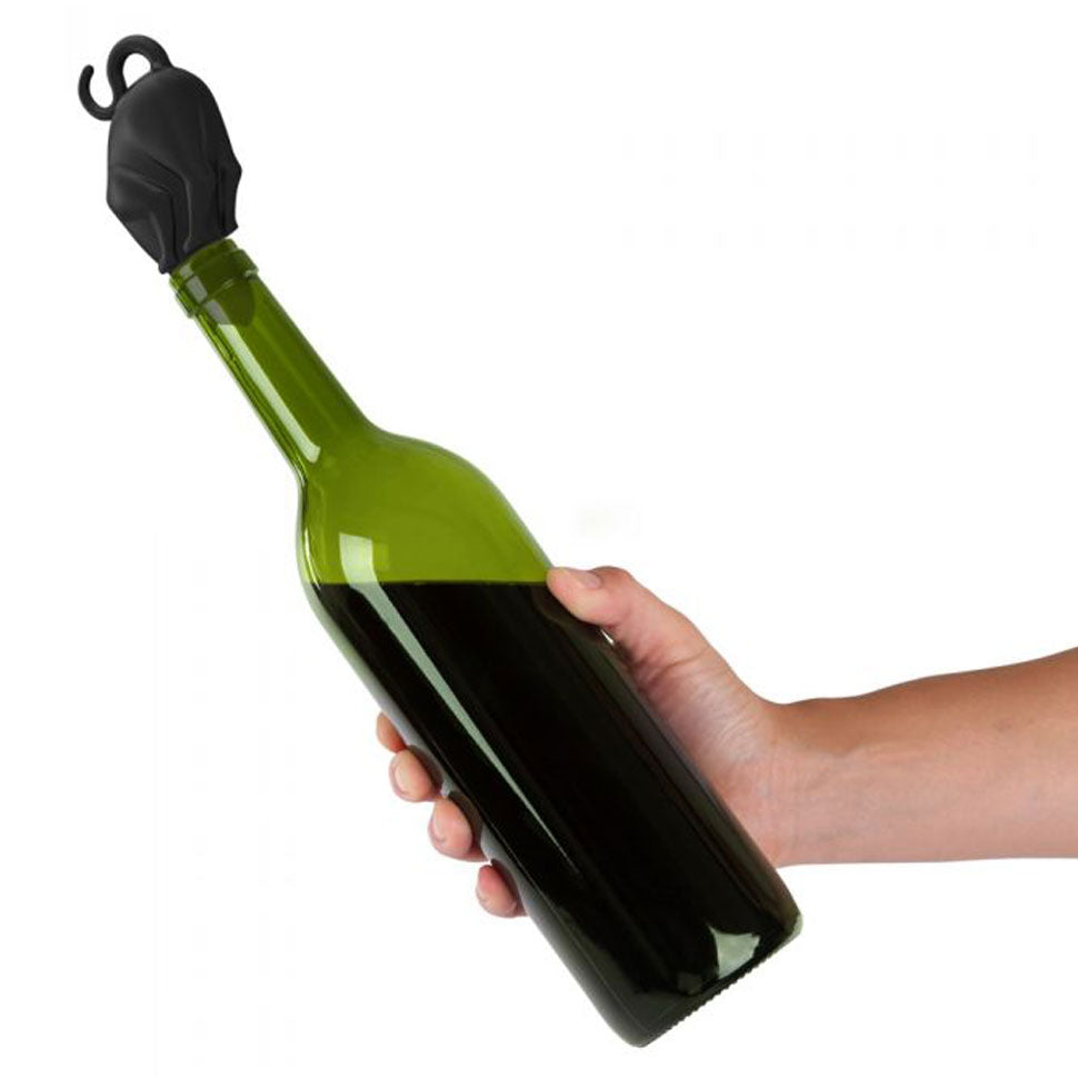 Model's hand holds a green wine bottle with a black silicone cat stopper stuck in the opening