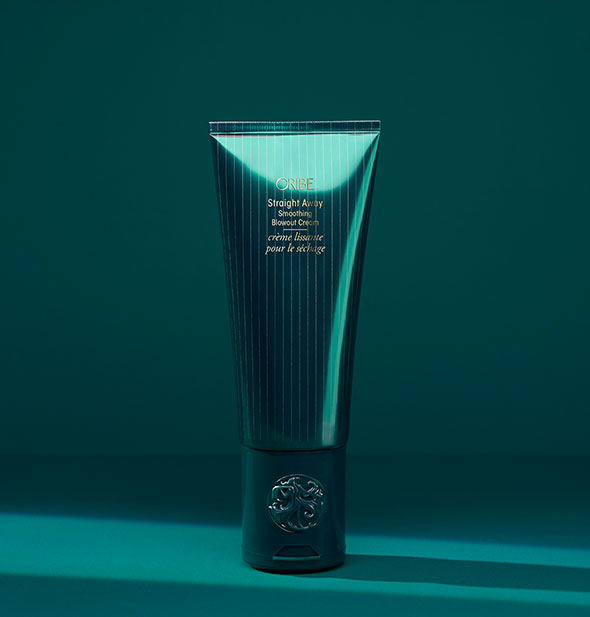Dark green striped teal bottle of Oribe Straight Away Smoothing Blowout Cream on teal background