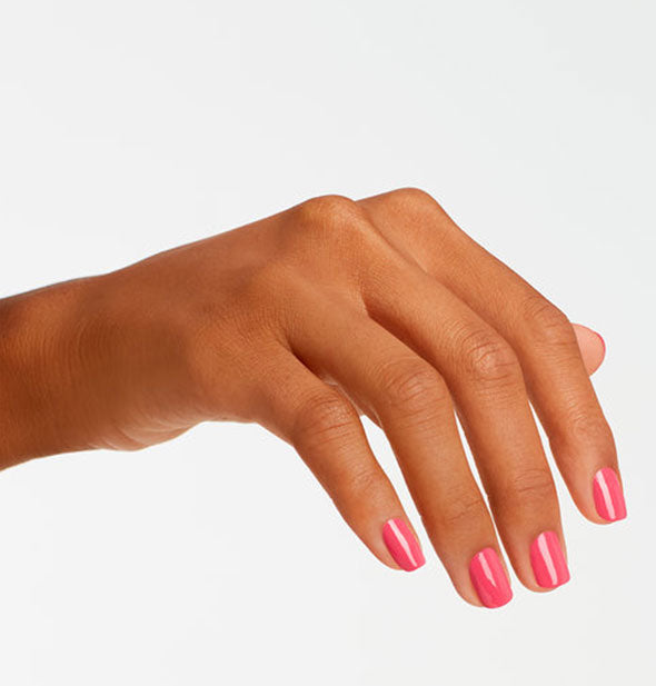 Model's hand wears an orangey-pink shade of nail polish