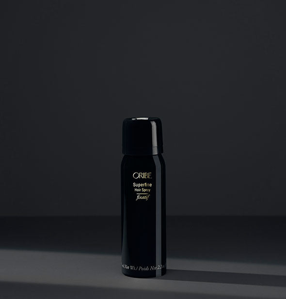 Small black can of Oribe Superfine Hair Spray on dark gray background