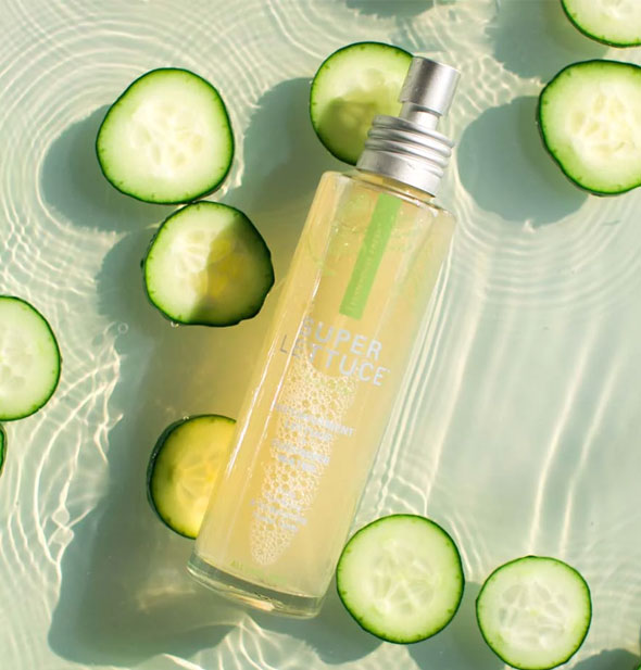 Bottle of Super Lettuce Facial Tonic rests in a clear pool of water with cucumber slices