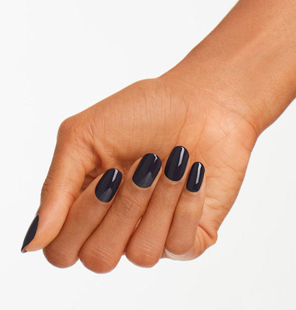 Model's hand wears a dark shade of purple-blue nail polish
