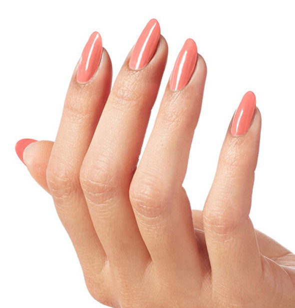 Model's hand wearing a coral shade of nail polish