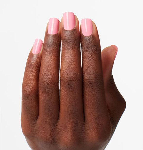 Model's hand wears a bubblegum pink shade of nail polish