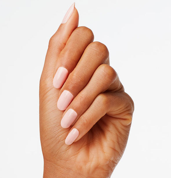 Model's hand wears a near-white shade of pink nail polish