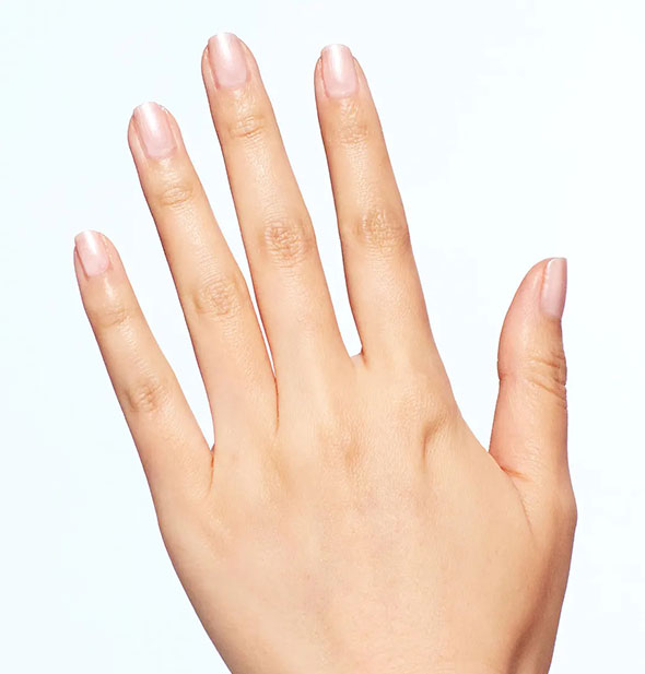 Model's hand wears a shimmery light pink shade of nail polish