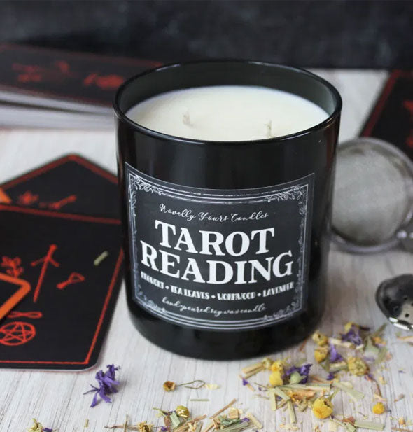 Tarot Reading candle with lid removed is staged with cards and dried flowers
