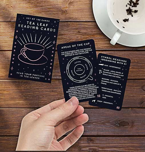 Model's hand holds a sample card from the Tea Leaf Reading deck