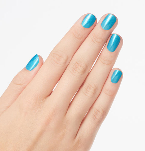 Model's hand wears a shimmery teal shade of nail polish