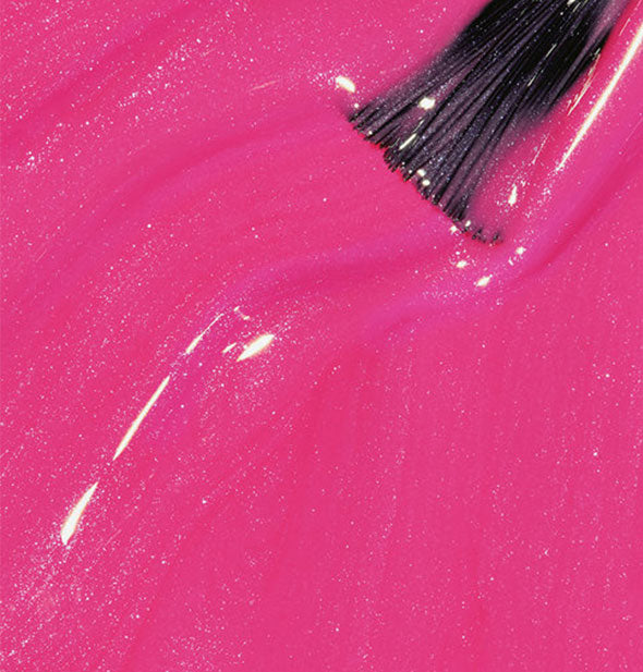 Shimmery magenta nail polish with brush tip drawn through it