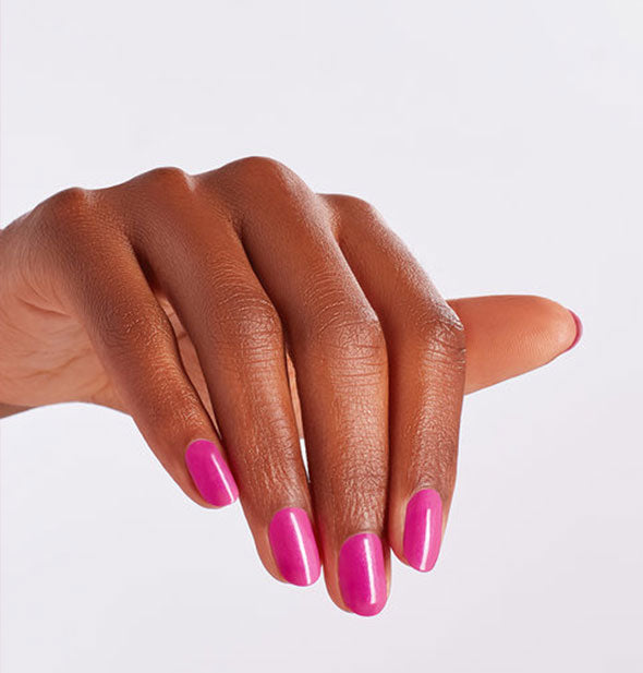 Model's hand wears a magenta shade of nail polish